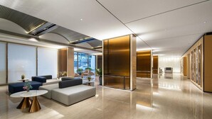 Eine moderne Lobby mit Sitzgelegenheiten, einem Empfangsbereich und Blick ins Freie.