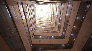 Una escalera de caracol con un muro espejado y suelo de baldosas.