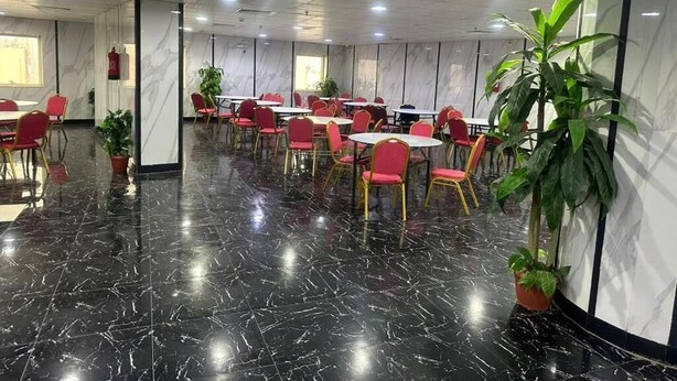 Un salón de conferencias con piso de mármol negro pulido, sillas rojas y mesas dispuestas para reuniones.