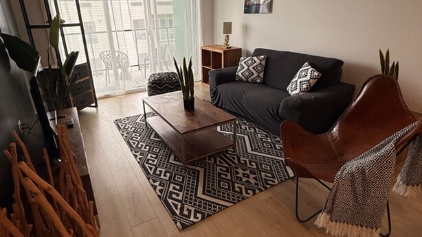 Una sala de estar con sofá, mesa de centro y alfombra estampada.