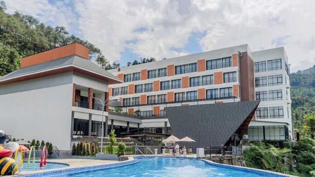 A modern hotel with a swimming pool, multiple floors, and a view of the surrounding greenery. - Gulala Azana Hotel and Resort Guci Tegal (Songgom)