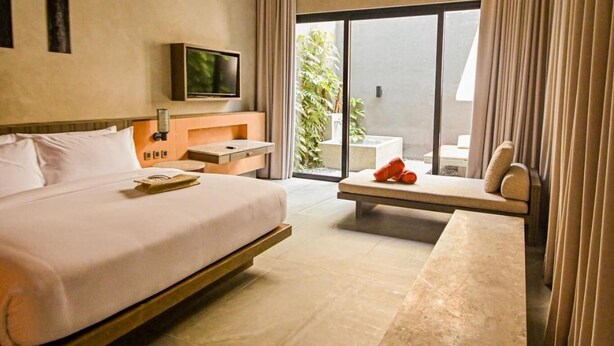 A modern hotel room with a large bed, a flat-screen TV, a desk, and a view of the outdoors. - Amorita Resort & Spa (Puerto Princesa)