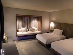 Une chambre d’hôtel comprenant un lit, un canapé-lit, une table de chevet et une fenêtre avec des rideaux.