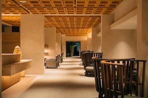 Un couloir avec un plafond en bois, des chaises et une plante en pot.