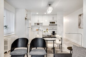 A modern kitchen with white cabinets, a dining table with chairs, and a pendant light. - Executive Suite 3BR - Close to Downtown Ottawa (Ottawa)