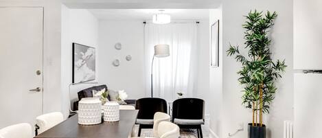 A modern dining area with a dark wooden table, white chairs, and decorative vases.