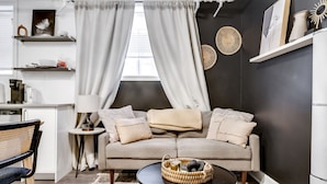 Un salon moderne comprenant un canapé, une table basse et un coin repas avec une chaise et une petite table.