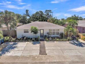A single-story house with a front entrance, a small garden with various plants, and a paved driveway. - Men Only Heated Pool & Spa - Prince @ Blue Lizard (Oakland Park)