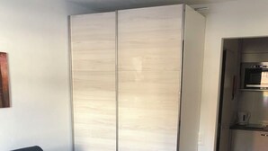 Ein kompakter Wohnbereich mit einer Couch, einer Küchenzeile und einem Schiebetürenschrank.