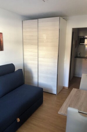 A compact living space with a sofa, a kitchenette, and a sliding wardrobe. - Cristallina I, (Laax Uletsch), 37021 by Interhome (Laax)