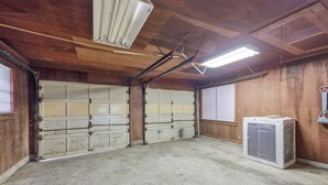 A garage with two large doors, a fluorescent light fixture, and a refrigerator.