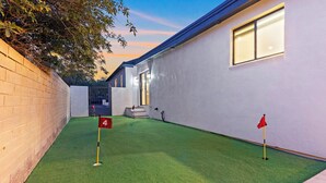 A building with a green artificial turf area, a brick wall, and a red flag marking a hole. - Luxury 5 BR Retreat. Sleeps 10+. Near U of A. (Tucson)