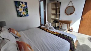 A hotel room with a bed, pillows, a painting, a desk, a mirror, and a wardrobe. - LaVilla Duo Ubud - 2 Private Pool Villas (Gianyar)