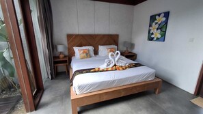 A bedroom with a wooden bed, white bedding, a headboard with a chevron pattern, two bedside tables with lamps, and a wall-mounted painting of flowers. - LaVilla Duo Ubud - 2 Private Pool Villas (Gianyar)