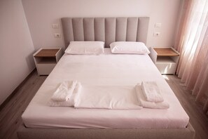 Ein ordentlich gemachtes Bett mit weißen Leinen und zwei am Fuß gefalteten Handtüchern.