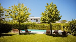 A pool area with lounge chairs and a modern house in the background. - Villa With Pool San Pietro Resort (Ishëm)
