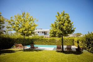 Ein Poolbereich mit Liegestühlen und einem modernen Haus im Hintergrund.