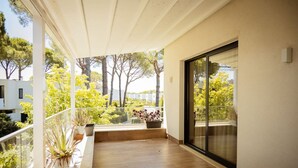 A balcony with wooden flooring, potted plants, and a view of trees and buildings. - Villa With Pool San Pietro Resort (Ishëm)