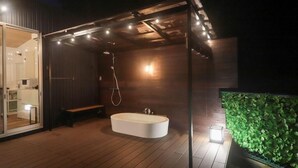 A modern outdoor bathroom with a freestanding bathtub, a bench, and a shower. - Well Resort Fuji Annex (Gotemba)