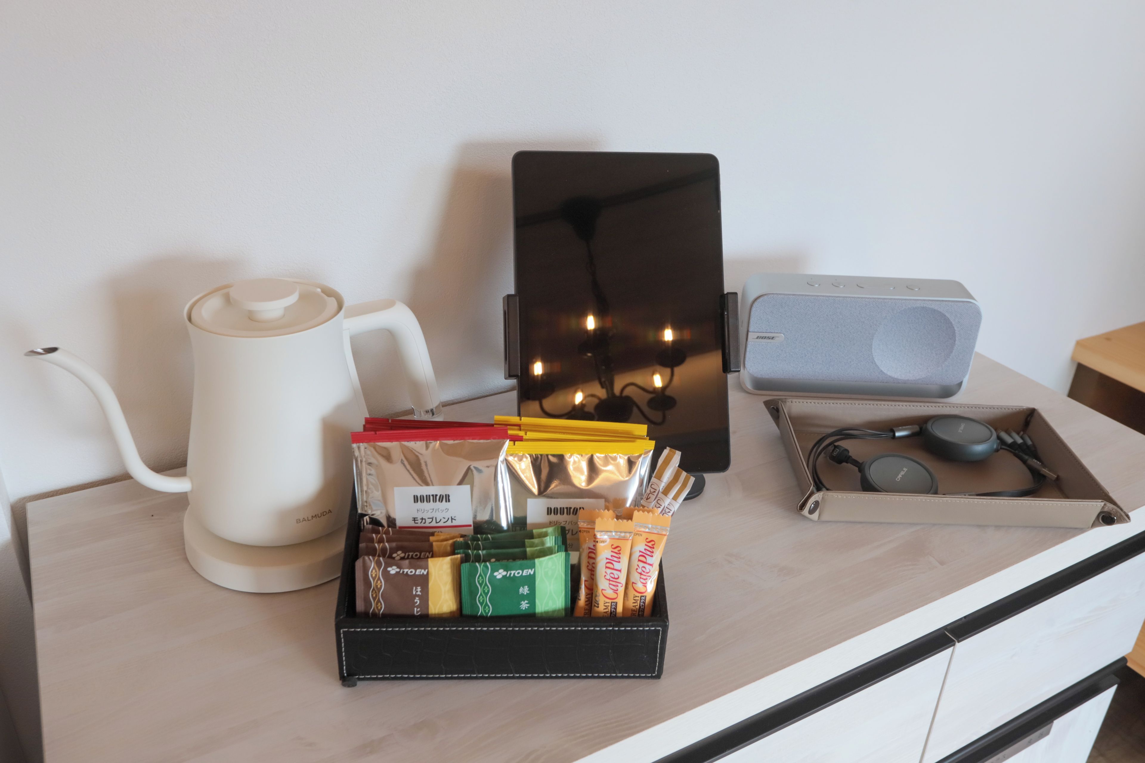 A kitchen counter with a coffee maker, a speaker, and a tray of snacks.