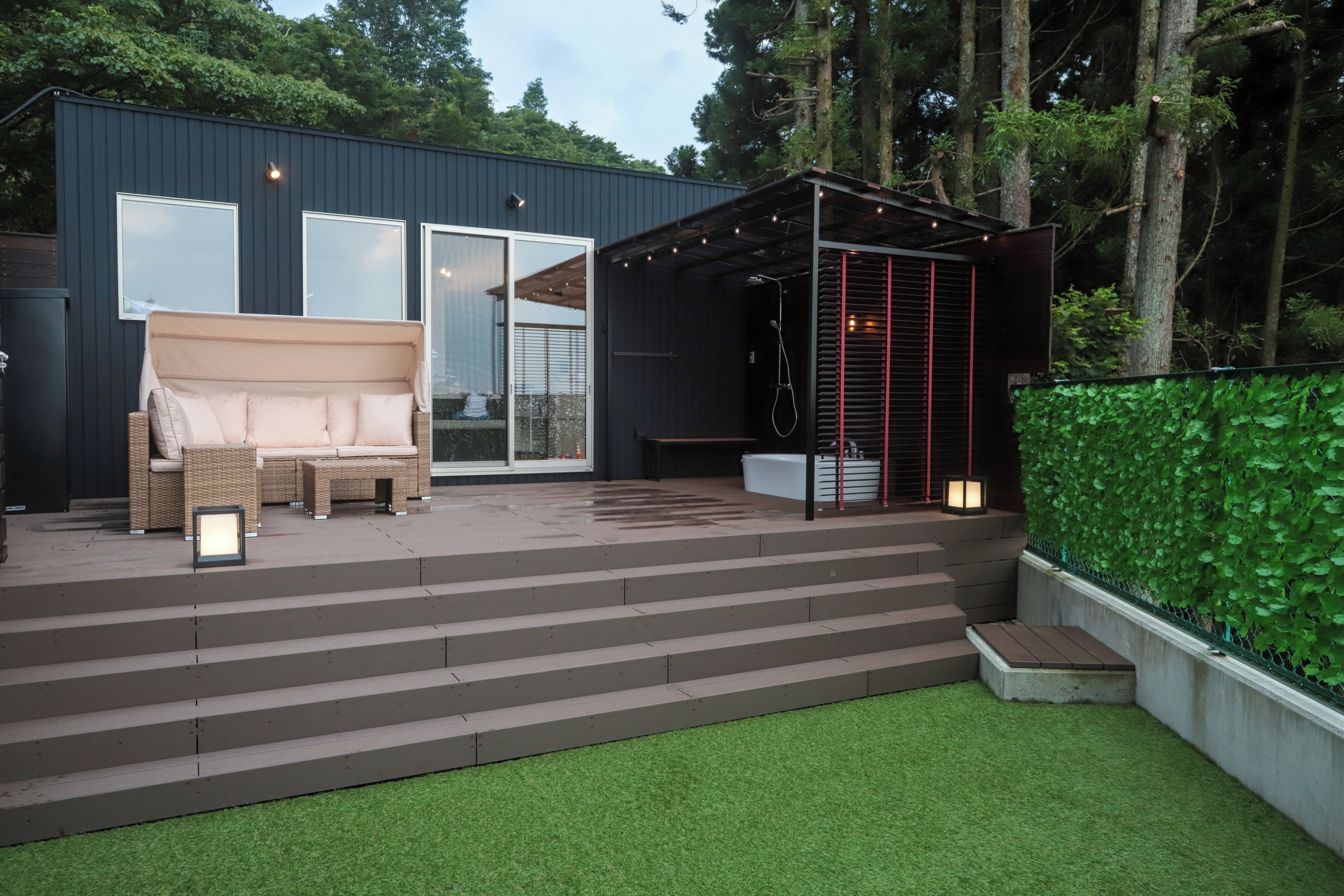 Un patio moderno al aire libre con sofá, escalones y una zona de estar cubierta.