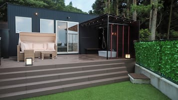 Un patio moderno al aire libre con sofá, escalones y una zona de estar cubierta.