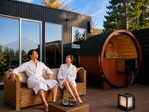 Um casal relaxando em um sofá de vime em frente a um edifício moderno com janelas amplas e sauna.