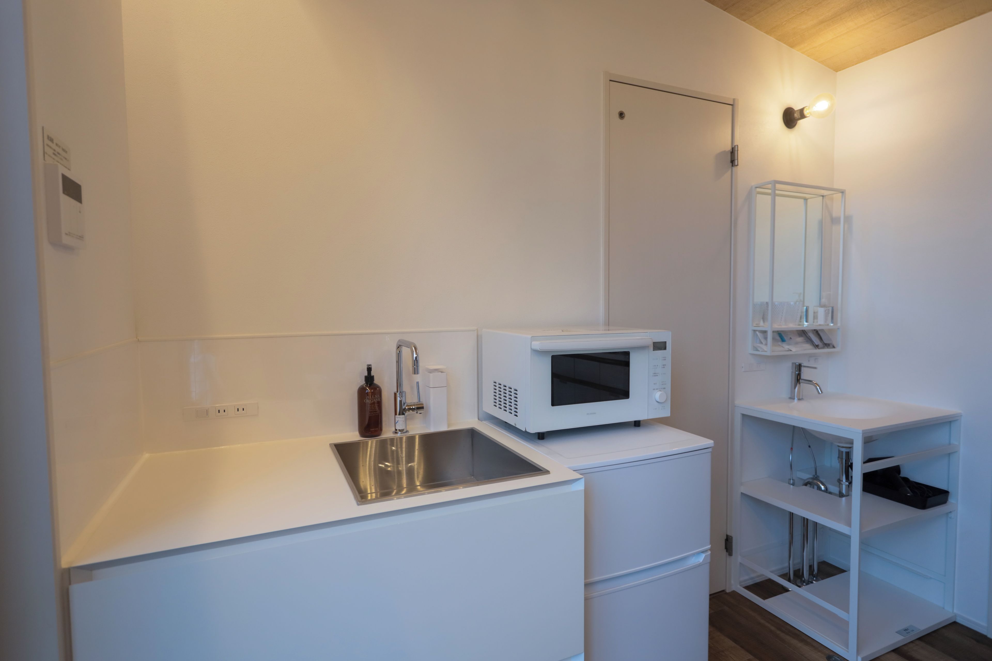A compact kitchenette with a microwave, sink, and a small cabinet.