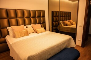 A bed with a tufted headboard, a bedside bench, and a mirror reflecting the bed. - Golden Pines Villa With Garden Perla Resort (Ishëm)