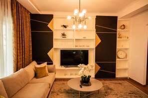 A living room with a sofa, a coffee table, a TV, and decorative shelves. - Golden Pines Villa With Garden Perla Resort (Ishëm)