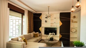 A modern living room with a sofa set, a coffee table, a TV, and decorative items. - Golden Pines Villa With Garden Perla Resort (Ishëm)