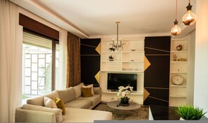 A modern living room with a sofa set, a coffee table, a TV, and decorative items. - Golden Pines Villa With Garden Perla Resort (Ishëm)