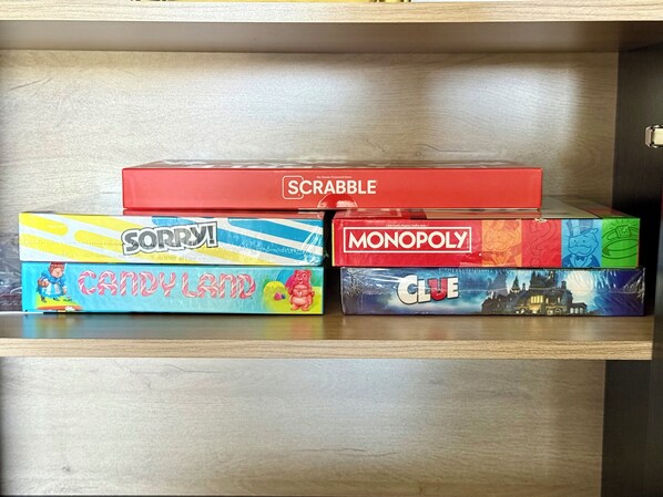 A shelf with four board games: Scrabble, Sorry!, Candy Land, Monopoly, and Clue. - One Block From Olde Town! Hot Tub, Fire Pit, Putting Green, Arcade & Game Room (Arvada)
