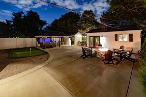 A residential backyard with a patio area, outdoor seating, and a hot tub. - One Block From Olde Town! Hot Tub, Fire Pit, Putting Green, Arcade & Game Room (Arvada)