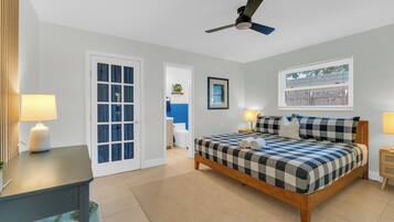 Un dormitorio con cama, lámparas de noche, ventilador de techo, ventana y puerta.