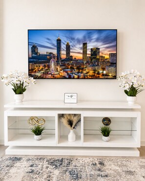 Ein zeitgemäßes Wohnzimmer mit Stadtbildgemälde, weißem Konsolentisch und zwei Orchideenvasen.