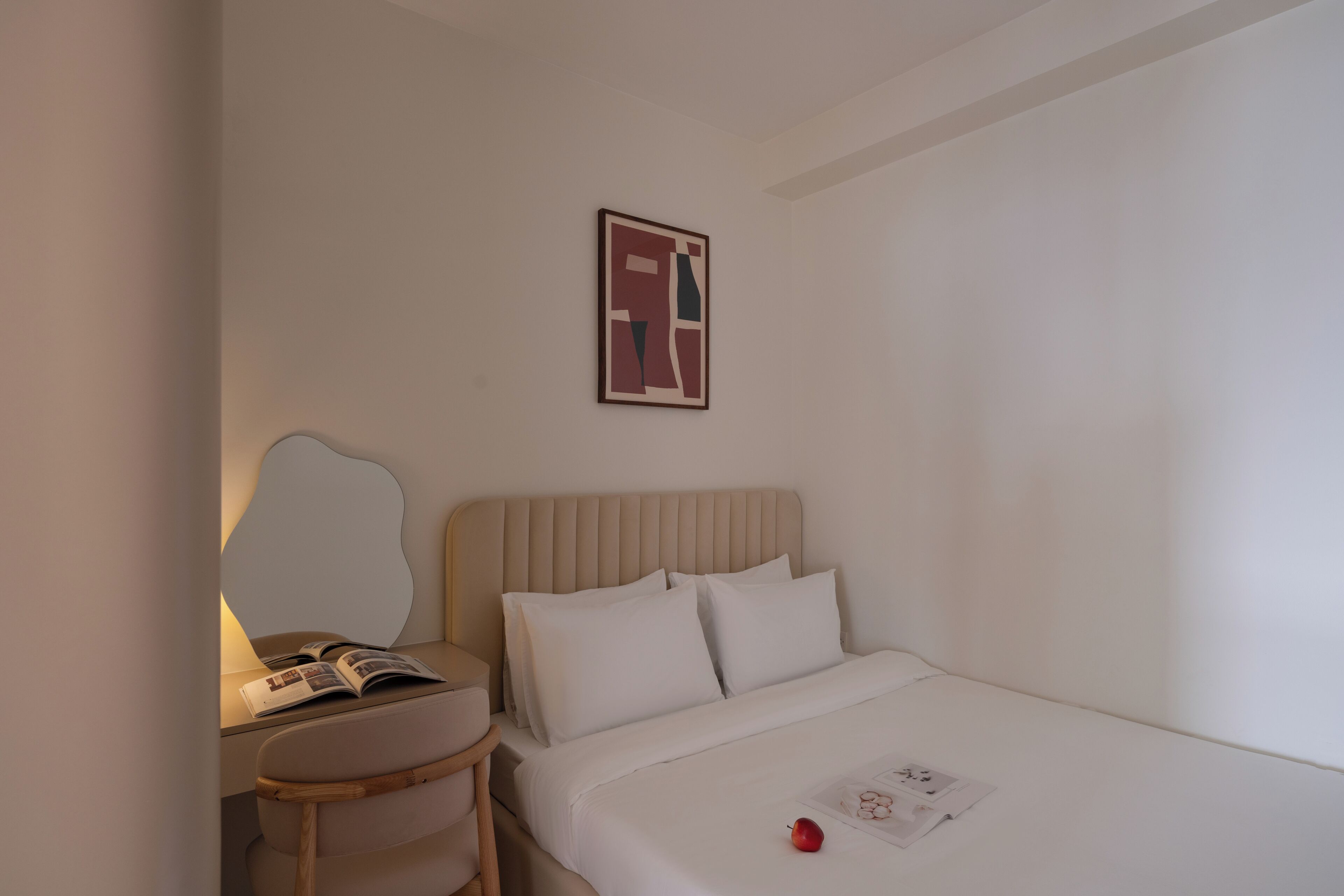 A hotel room with a bed, a bedside table with a lamp, a chair, and a wall-mounted picture.