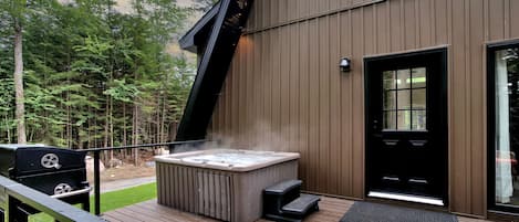 A hot tub on a wooden deck with a modern building in the background.
