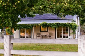 Una casa con paneles solares, un porche cubierto y un patio cercado.