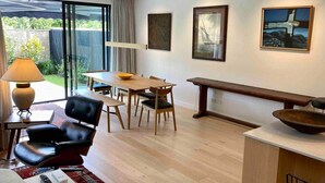 Un soggiorno moderno con zona pranzo, una panca e opere d'arte alle pareti.