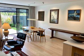 A modern living room with a dining area, a bench, and artwork on the walls. - Stylish Townhouse in Grey Lynn close to central city (Auckland)