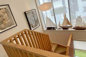 A wooden chair in a room with a window, a framed picture, and a model sailboat on a shelf. - Stylish Townhouse in Grey Lynn close to central city (Auckland)