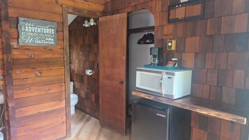 Una cocina pequeña equipada con microondas, cafetera y refrigerador.