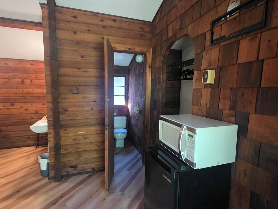 A wooden interior with a sink, toilet, and a white refrigerator.