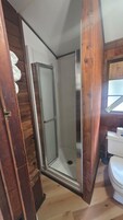 Un baño con ducha, inodoro y paredes de madera.