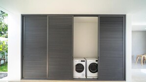 A modern interior with a large sliding wardrobe and a washing machine in the center. - Coco Villas - 3BR Deluxe Pool Villas  (Thep Krasattri)