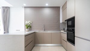 A modern kitchen with a built-in oven, microwave, and a sink. - Coco Villas - 3BR Deluxe Pool Villas  (Thep Krasattri)