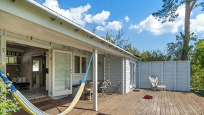 Un terrazzo in legno con un'amaca, un'altalena e una zona patio coperta.