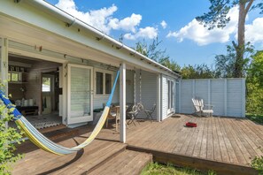 Eine Holzterrasse mit einer Hängematte, einer Schaukel und einem überdachten Patio.
