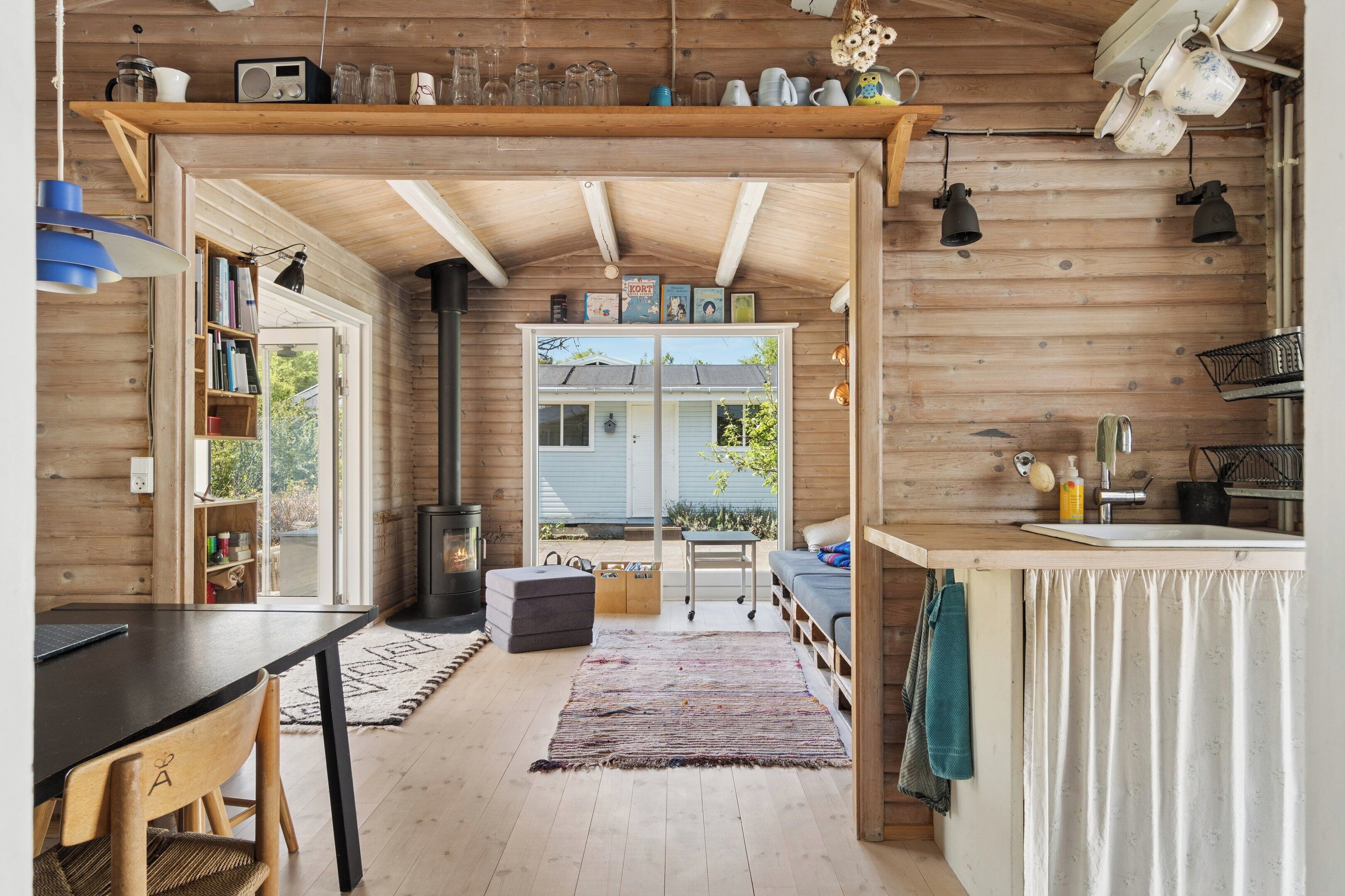 Interior acogedor de una cabaña con detalles de madera, un comedor, una cocina con fregadero y una chimenea.